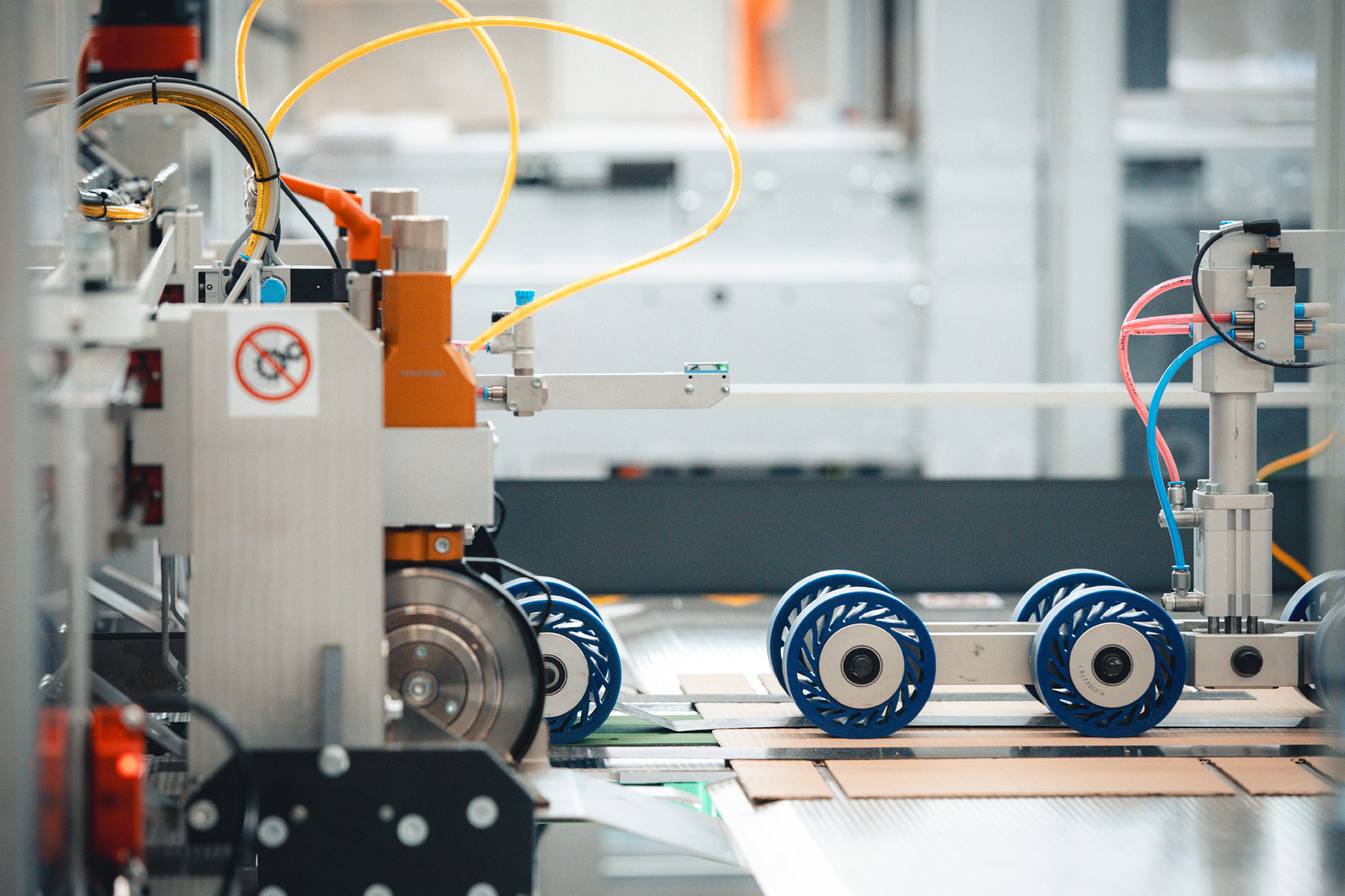 Blue guide rollers and yellow tubing mounted along a machine frame.