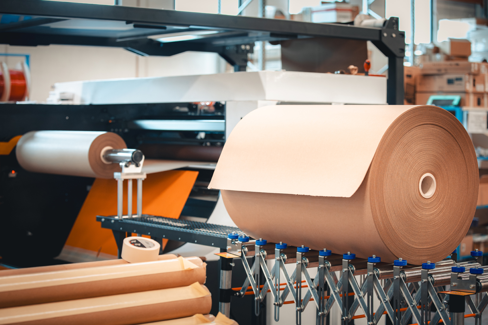Brown paper feeding from a large reel through a machine.